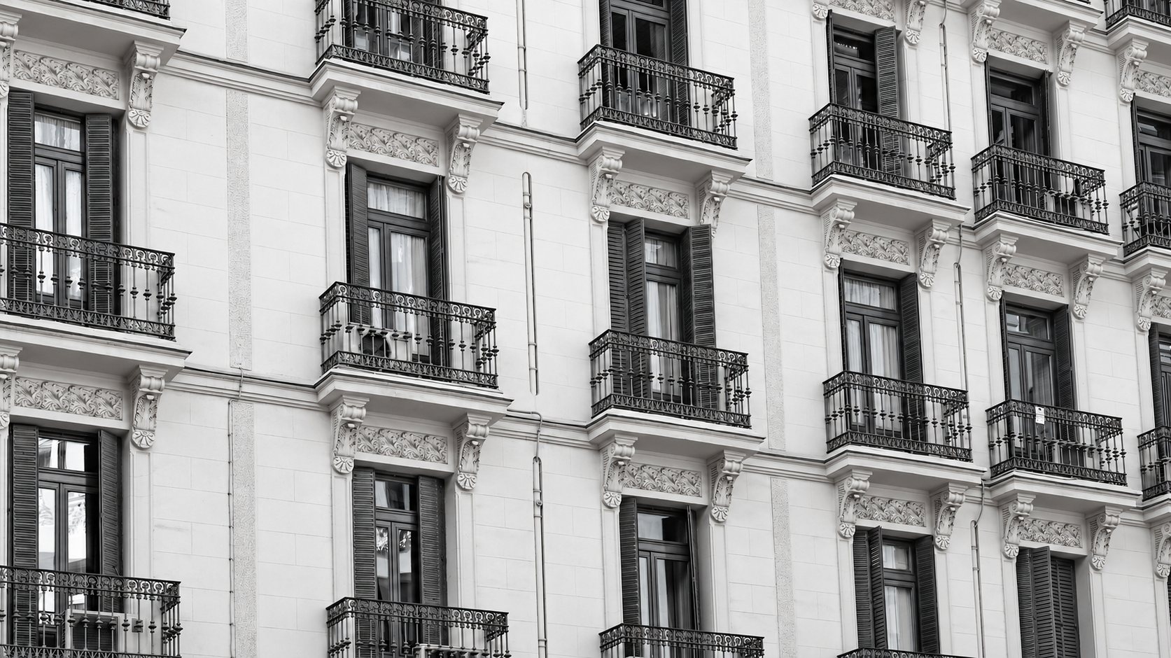 Façade d’un immeuble ancien aux balcons en fer forgé, en noir et blanc
