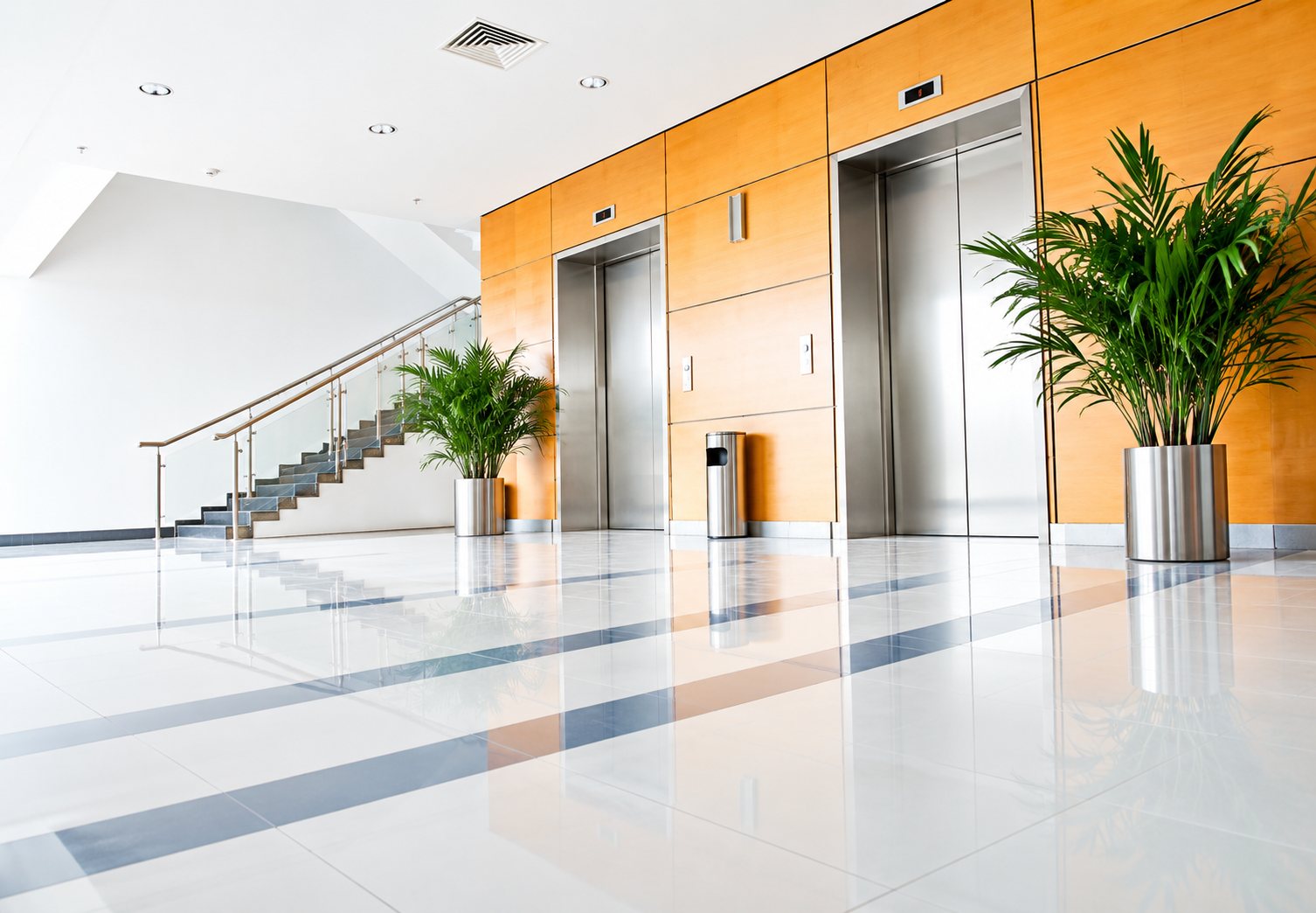 Hall d’entrée avec ascenseurs, plantes vertes et escalier